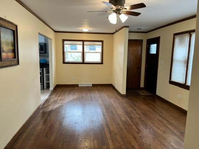 interior space featuring visible vents, crown molding, baseboards, and wood finished floors