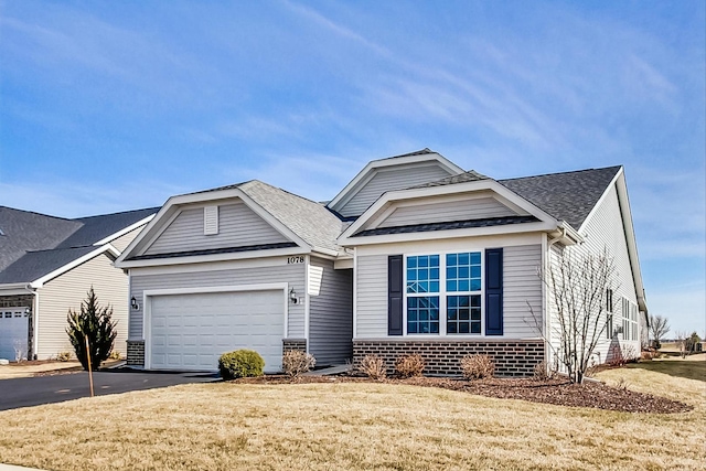 view of front of property featuring aphalt driveway, brick siding, a shingled roof, a garage, and a front lawn