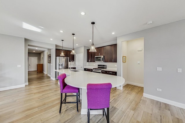 kitchen with stainless steel appliances, light wood-type flooring, a sink, and a kitchen bar