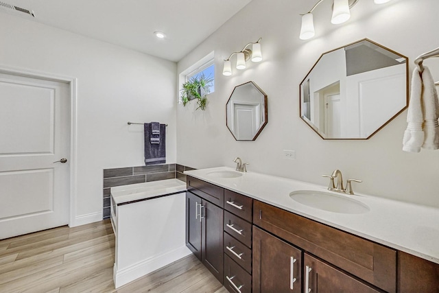 full bathroom with double vanity, wood finished floors, a sink, and visible vents