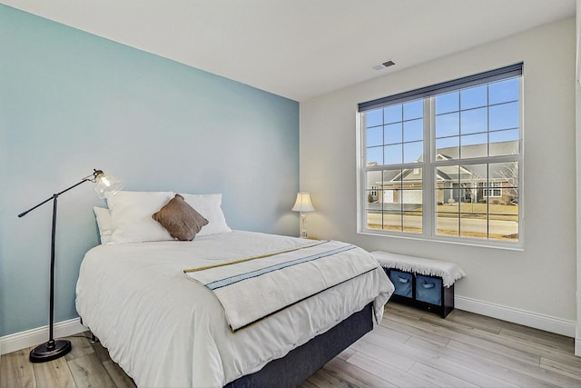 bedroom featuring visible vents, baseboards, and wood finished floors