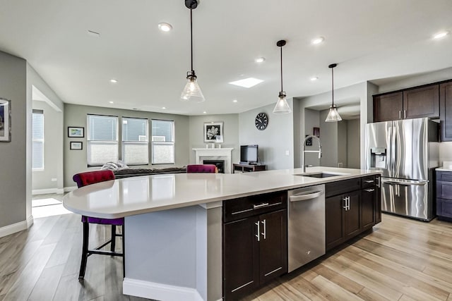 kitchen with an island with sink, stainless steel appliances, a sink, and open floor plan