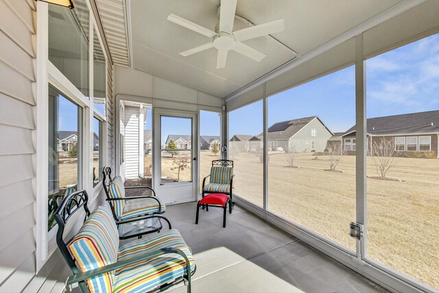 sunroom featuring ceiling fan, a residential view, and vaulted ceiling