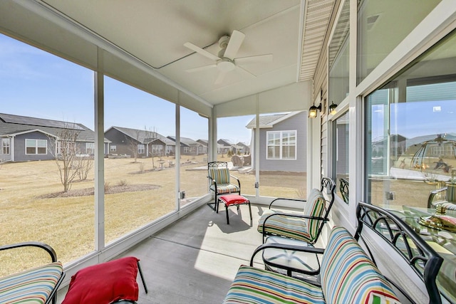 sunroom with vaulted ceiling, a residential view, and a ceiling fan