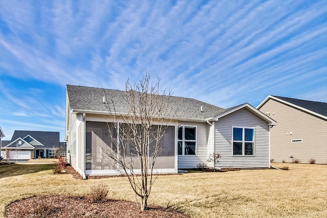 rear view of property featuring a sunroom, roof with shingles, and a yard