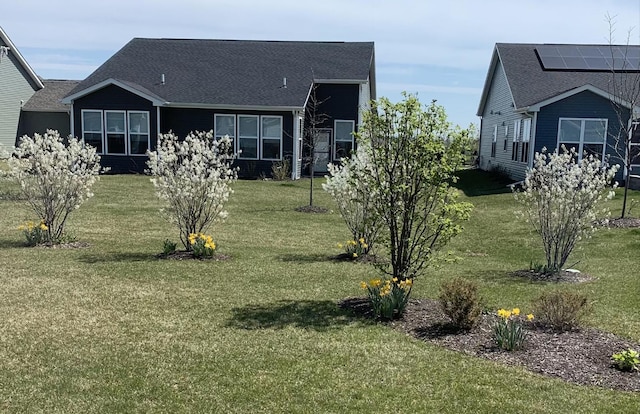 exterior space with roof with shingles and a front yard