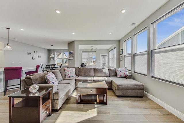 living room with a healthy amount of sunlight, light wood-style floors, baseboards, and visible vents