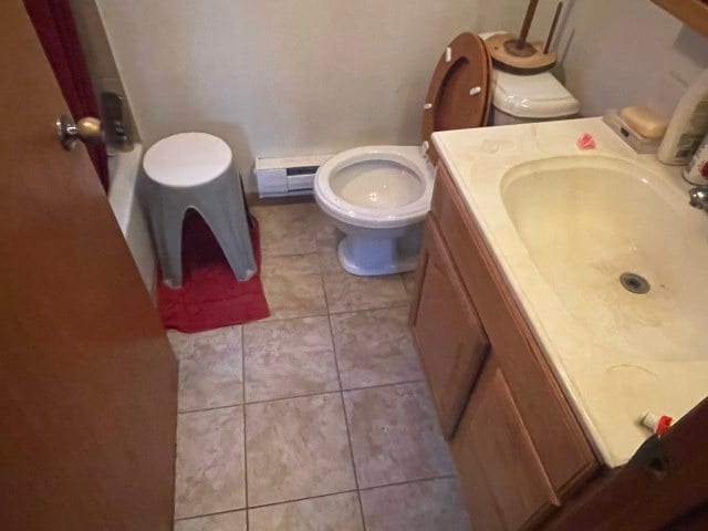 bathroom with a baseboard heating unit, a sink, tile patterned flooring, and toilet