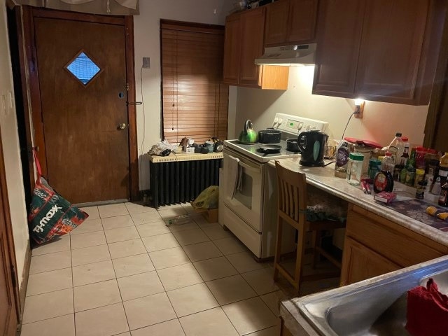 kitchen featuring light tile patterned floors, light countertops, white range with electric stovetop, and under cabinet range hood