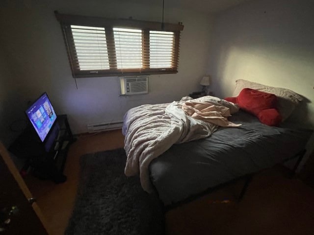 bedroom featuring a baseboard heating unit and cooling unit