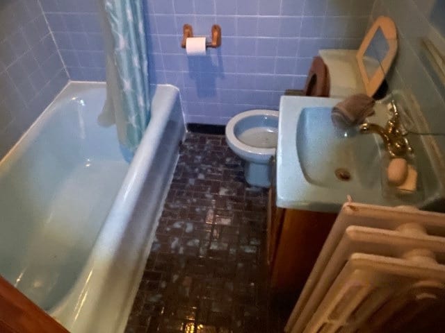 full bathroom featuring vanity, toilet, and tile walls