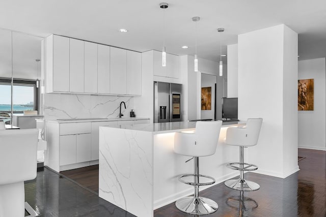 kitchen featuring white cabinets, a peninsula, stainless steel fridge with ice dispenser, and modern cabinets