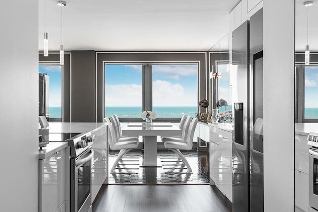 kitchen with a water view, wood finished floors, white cabinets, and stainless steel electric stove