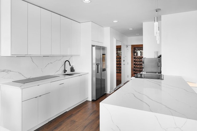 kitchen with stainless steel fridge, a sink, backsplash, and light stone countertops