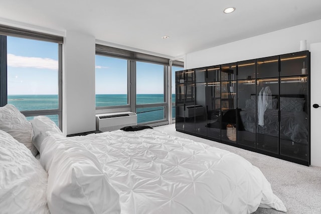 carpeted bedroom with recessed lighting, a wall unit AC, and a water view