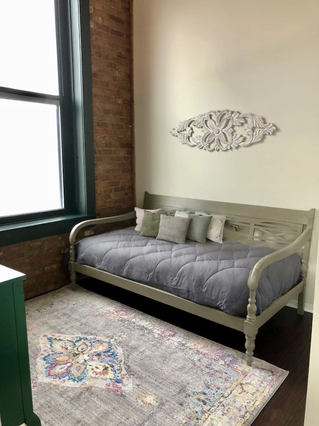 bedroom with brick wall and wood finished floors