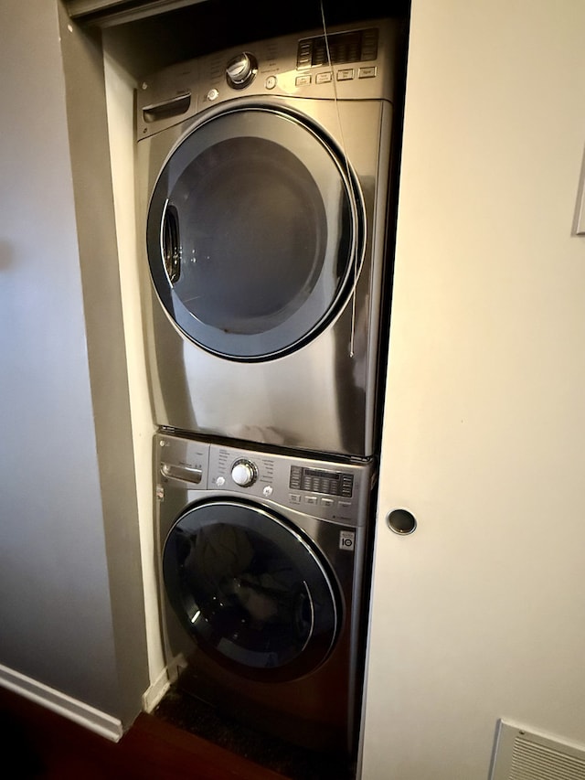 washroom featuring stacked washer and dryer, baseboards, and laundry area