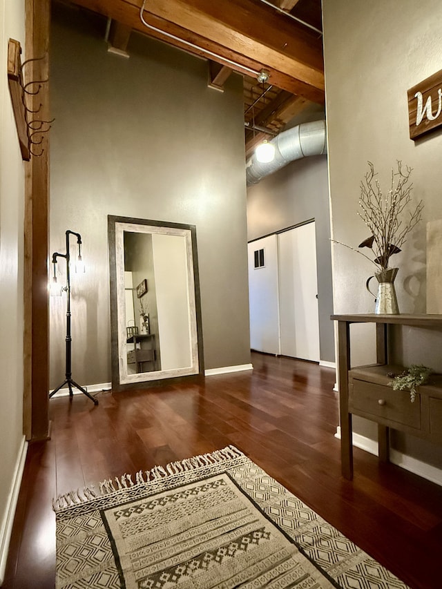 hall featuring visible vents, wood finished floors, a towering ceiling, and baseboards