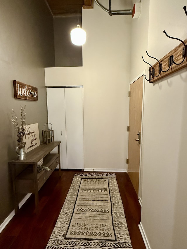 interior space with a towering ceiling, baseboards, and wood finished floors