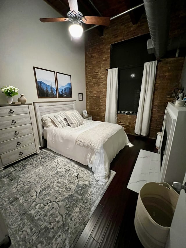 bedroom with brick wall, dark wood finished floors, and a ceiling fan