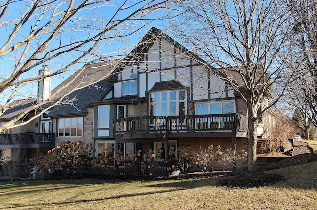 back of property with brick siding, a lawn, and a wooden deck