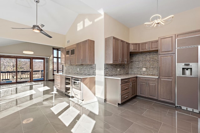 kitchen featuring paneled built in fridge, tasteful backsplash, beverage cooler, light countertops, and high vaulted ceiling