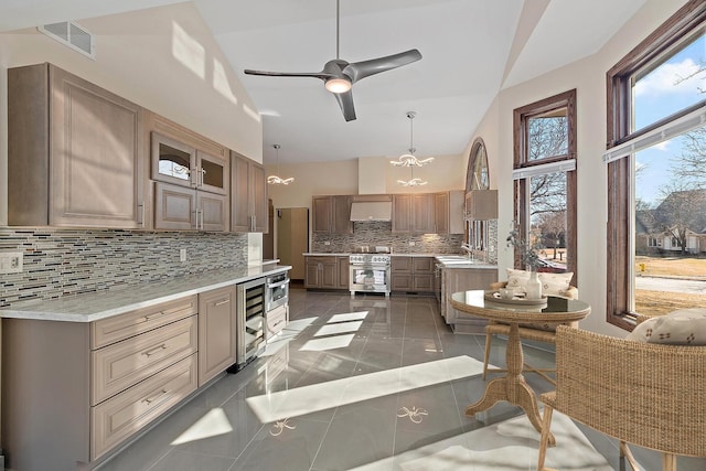 kitchen featuring beverage cooler, a sink, visible vents, high end stainless steel range, and decorative backsplash