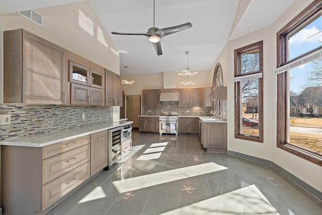 kitchen featuring wine cooler, tasteful backsplash, visible vents, a sink, and high end stove