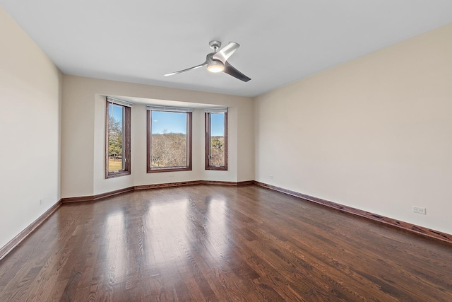 empty room featuring a ceiling fan, baseboards, and wood finished floors