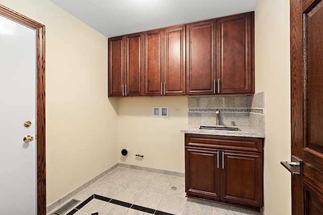 clothes washing area featuring hookup for a washing machine, hookup for a gas dryer, a sink, baseboards, and cabinet space