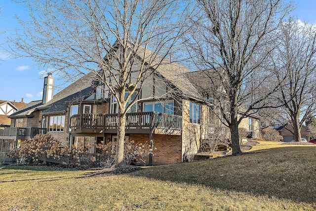 rear view of property featuring a chimney, a lawn, and brick siding