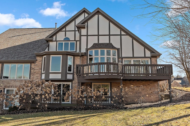 back of house with a shingled roof, brick siding, a yard, and stucco siding