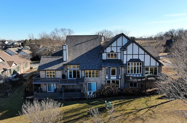 rear view of property featuring a yard, a shingled roof, a chimney, and a balcony