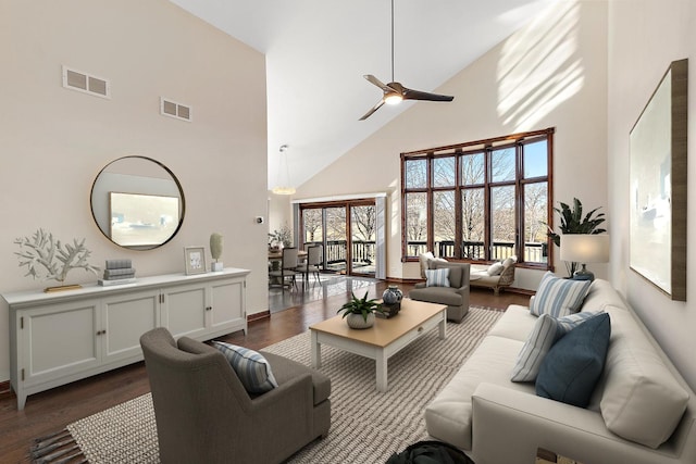 living room with dark wood-style floors, high vaulted ceiling, visible vents, and a ceiling fan