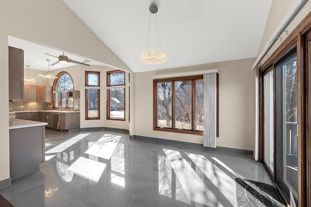 unfurnished dining area with ceiling fan, high vaulted ceiling, a sink, baseboards, and marble finish floor