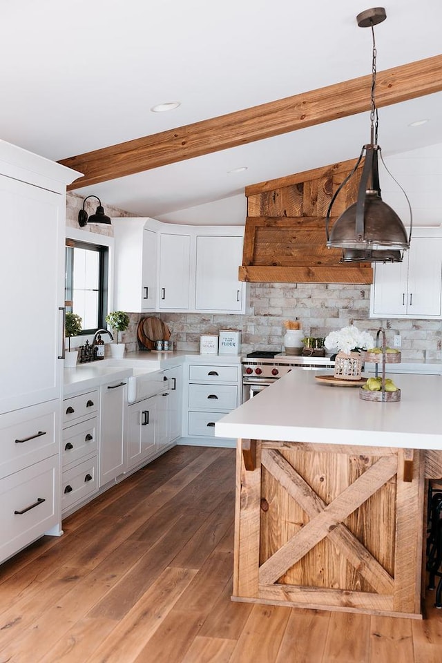 kitchen featuring a breakfast bar, white cabinets, light countertops, high end range, and light wood finished floors