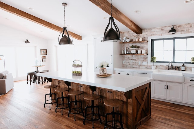 kitchen featuring a kitchen bar, dark wood-type flooring, a sink, and light countertops