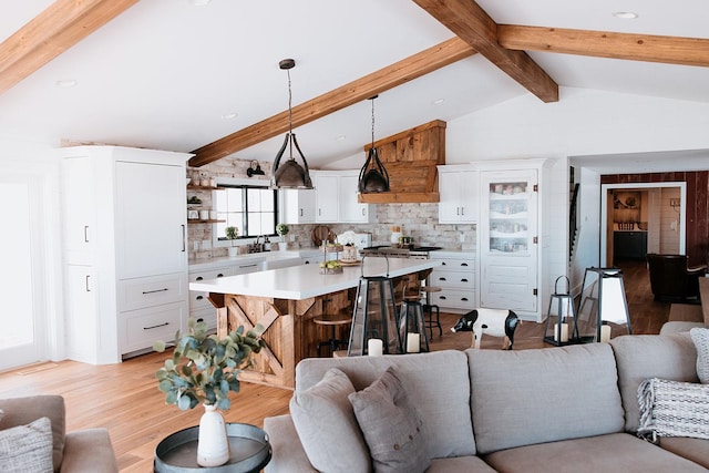 living room with vaulted ceiling with beams and light wood-type flooring