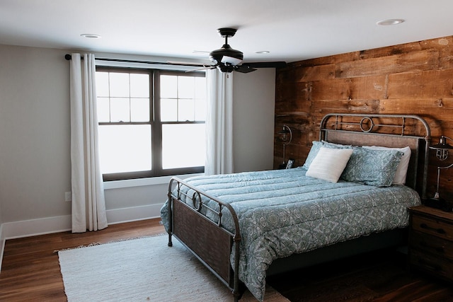 bedroom featuring recessed lighting, wood walls, baseboards, and wood finished floors