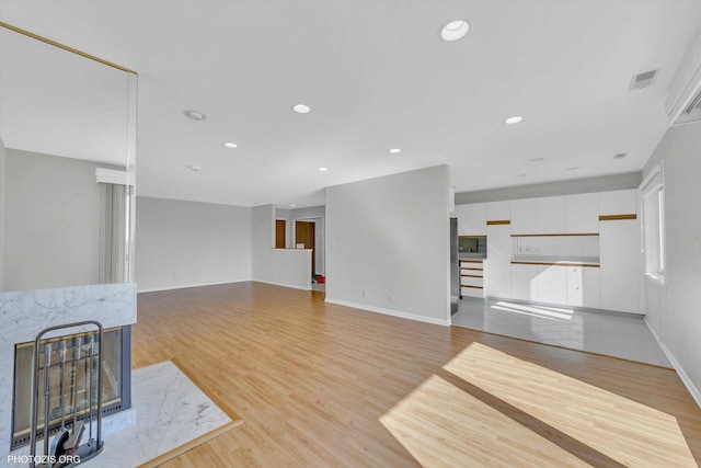 unfurnished living room featuring light wood finished floors, a fireplace, visible vents, and recessed lighting