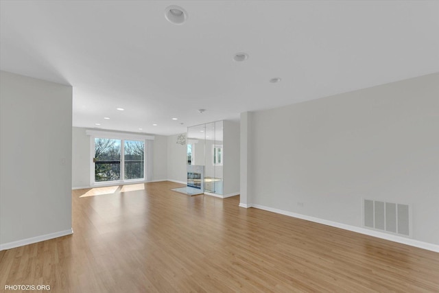 unfurnished living room featuring light wood-style flooring, recessed lighting, a fireplace, visible vents, and baseboards