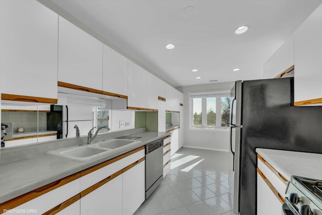 kitchen featuring stainless steel appliances, light countertops, white cabinetry, a sink, and light tile patterned flooring