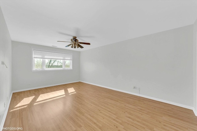 empty room with ceiling fan, baseboards, and wood finished floors