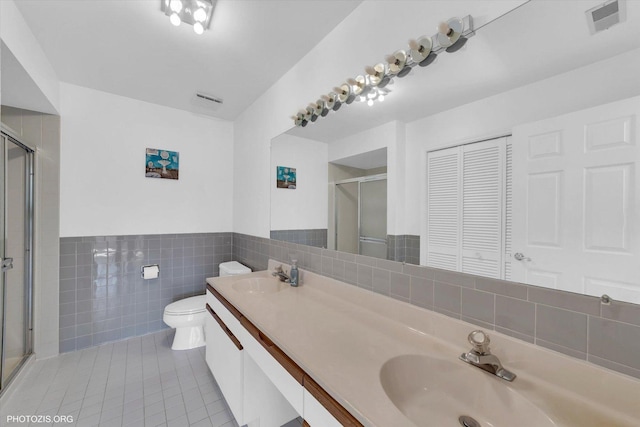 full bath with tile walls, a sink, toilet, and tile patterned floors