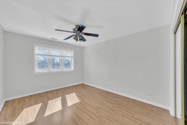 spare room with visible vents, wood finished floors, a ceiling fan, and baseboards