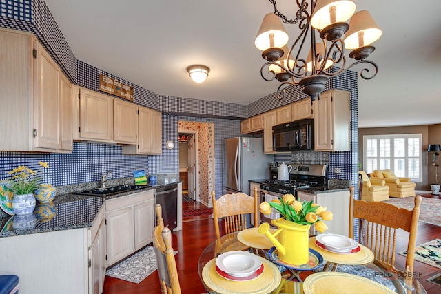 kitchen with wallpapered walls, dark wood-style flooring, stainless steel appliances, a chandelier, and a sink