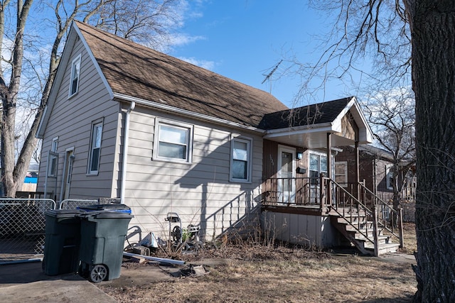 exterior space with roof with shingles, fence, and stairway