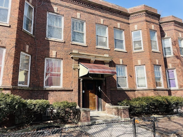 view of front facade with fence and brick siding