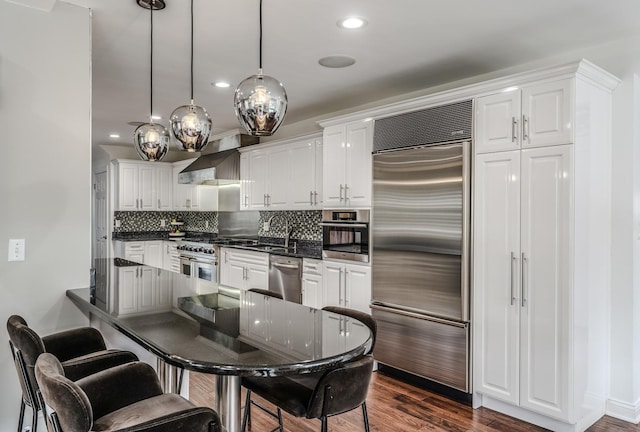 kitchen featuring dark wood-style flooring, dark countertops, high quality appliances, and white cabinets