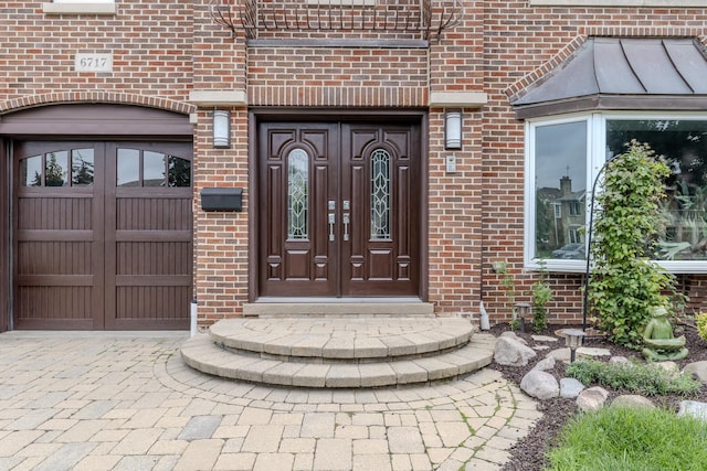 property entrance featuring a garage and brick siding